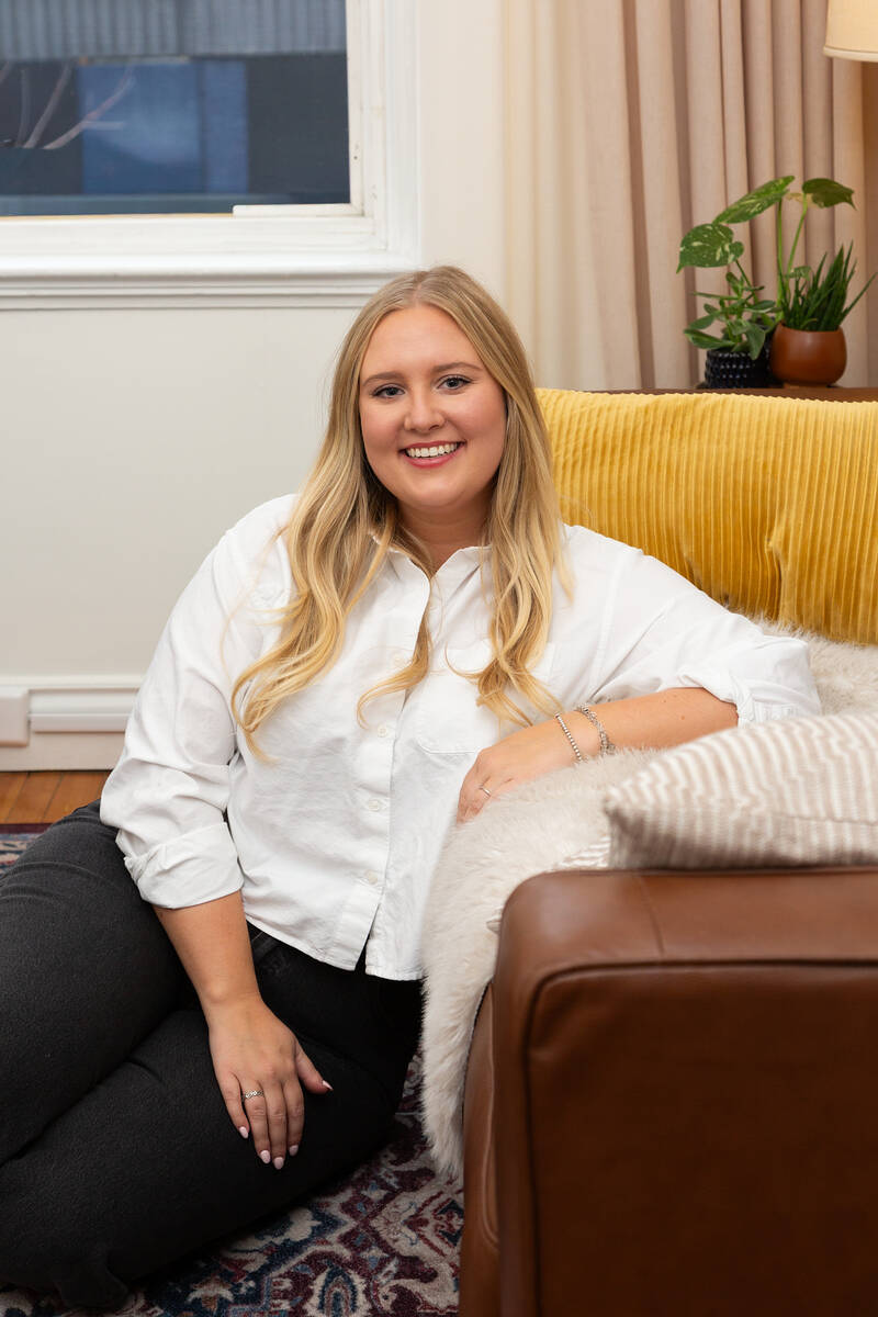 Madison Troian sitting on the floor leaning against a couch
